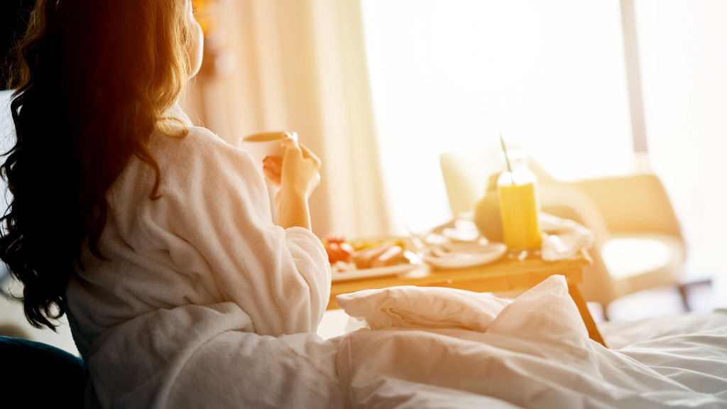 Hotellfrukost på sängen. Härligt gult solljus som skiner in i rummet.