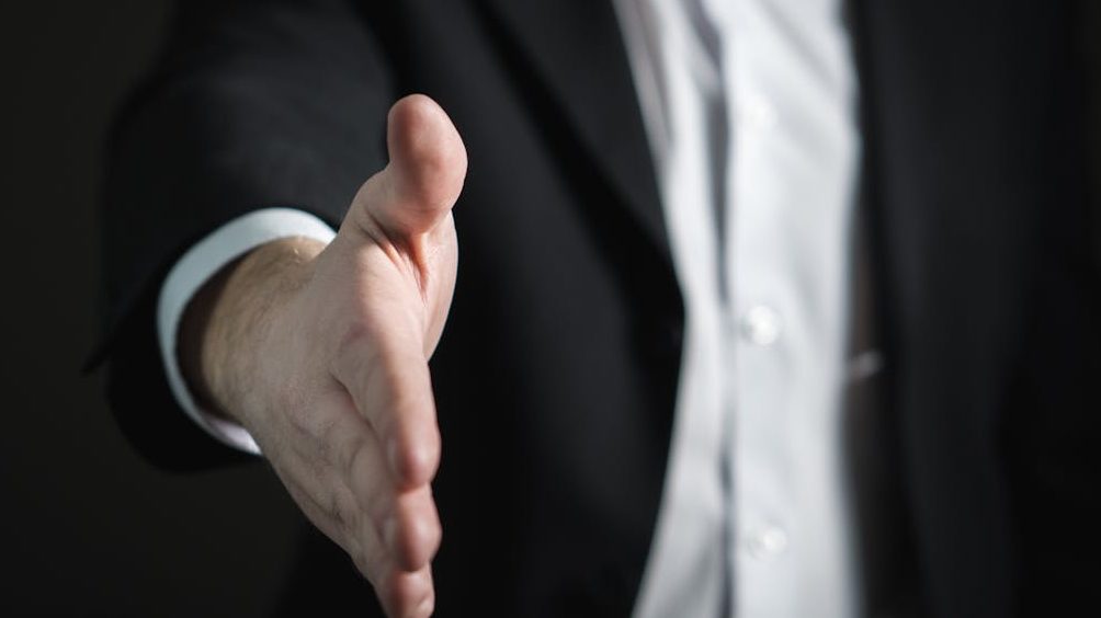 Close-up of a businessman extending hand for a handshake, symbolizing agreement and partnership.